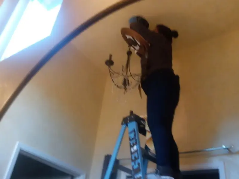 Electrician installing a chandelier in a Berlin residence